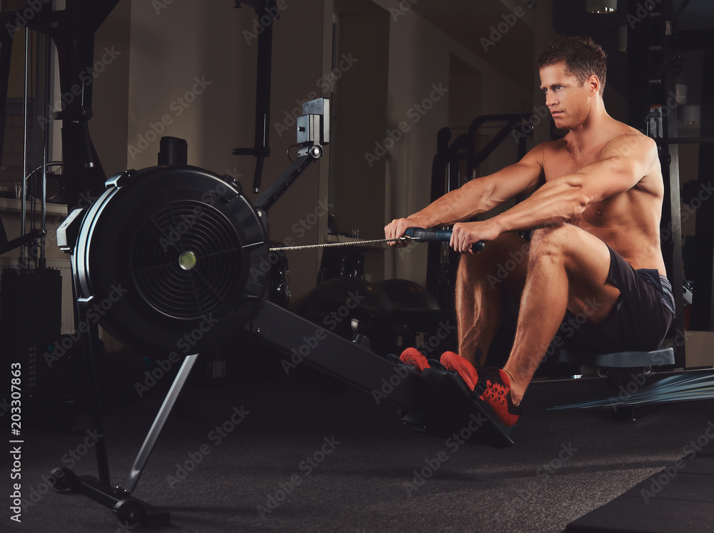 Handsome muscular fitness male doing exercise on the rowing machine. Handsome muscular fitness male doing exercise on the rowing machine.