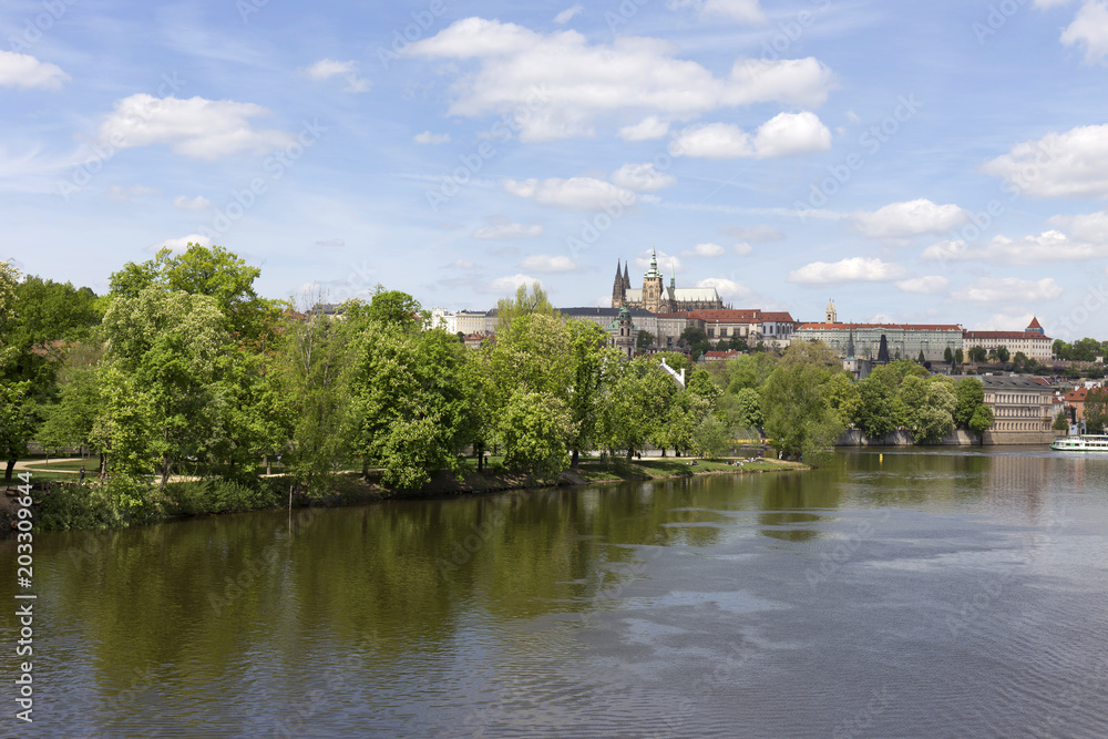 Spring green Prague Lesser Town with gothic Castle and Charles Bridge above River Vltava in the sunny Day, Czech Republic