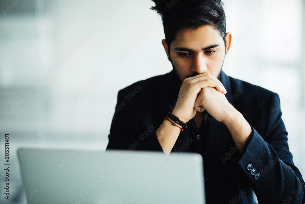 Concetrated indian man smiling and working at office Concetrated indian man smiling and working at office