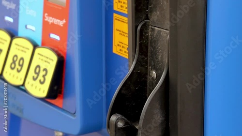 Close up on gas pump as hand lift out pump nozzle.