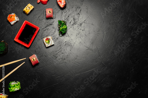 Top view of Japanese Sushi and chopsticks on black background. Sushi rolls, nigiri, maki, pickled ginger, wasabi, soy sauce. Space for text. Top view. Sushi background. food frame