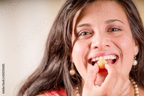 Portrait of woman wearing a pink blouse and eating a star gooseberry fruit. Phyllanthus acidus, known as the Otaheite gooseberry, star, damsel, grosella, karamay