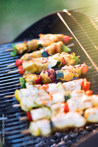 close-up of a barbecue where chicken skewers are being cooked.