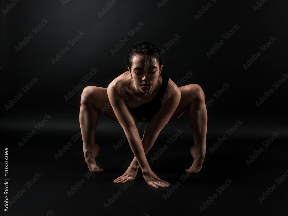 Sporty fit darkhair woman in black sportswear working out in studio with black background. Dancing, streching, Standing pilates, yoga and fitness poses
