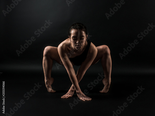 Sporty fit darkhair woman in black sportswear working out in studio with black background. Dancing, streching, Standing pilates, yoga and fitness poses