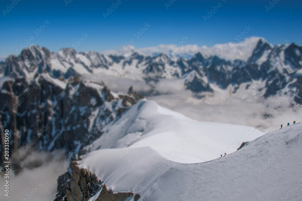 Snowy peaks and mountaineers, viewed from the Aiguille du Midi, near Chamonix. A famous ski resort located in Haute-Savoie Province, at the foot of Mont Blanc in the French Alps. Retouched photo.