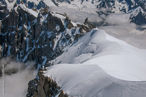 Snowy peaks and mountains in a sunny day, viewed from the Aiguille du Midi, near Chamonix. A famous ski resort located in Haute-Savoie Province, at the foot of Mont Blanc in the French Alps.