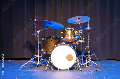 Classic professional basic drum kit set on a stage with black curtains in the background.