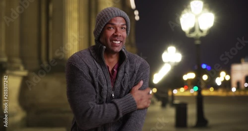Young black man in Paris shivering outside on a cold night, African male traveling in Paris, France standing outside in winter clothes on a freezing night, 4k