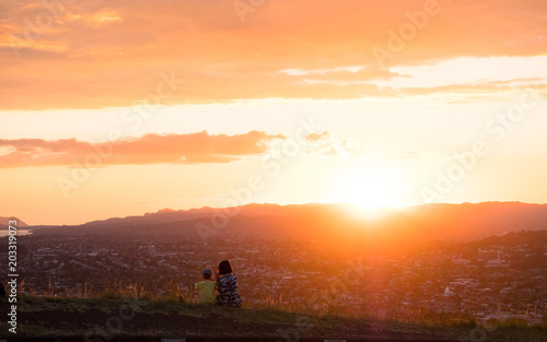 Mom and son enjoy together their sunset over the mountain and the town.