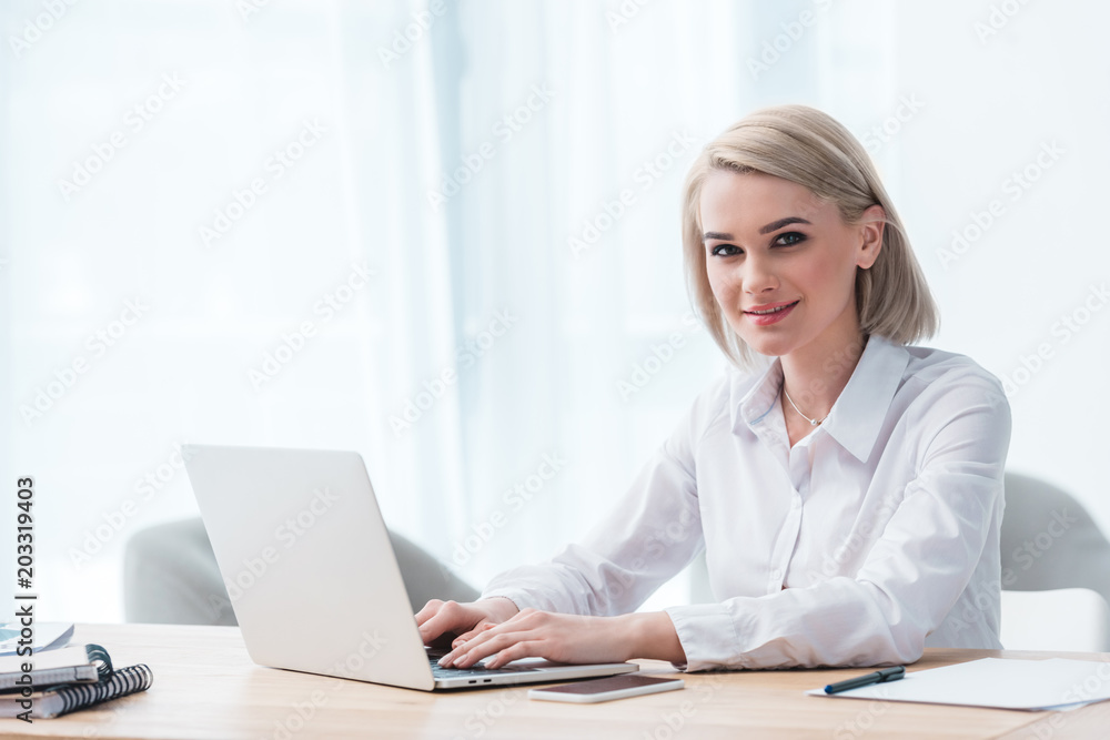 beautiful young businesswoman using laptop and smiling at camera beautiful young businesswoman using laptop and smiling at camera