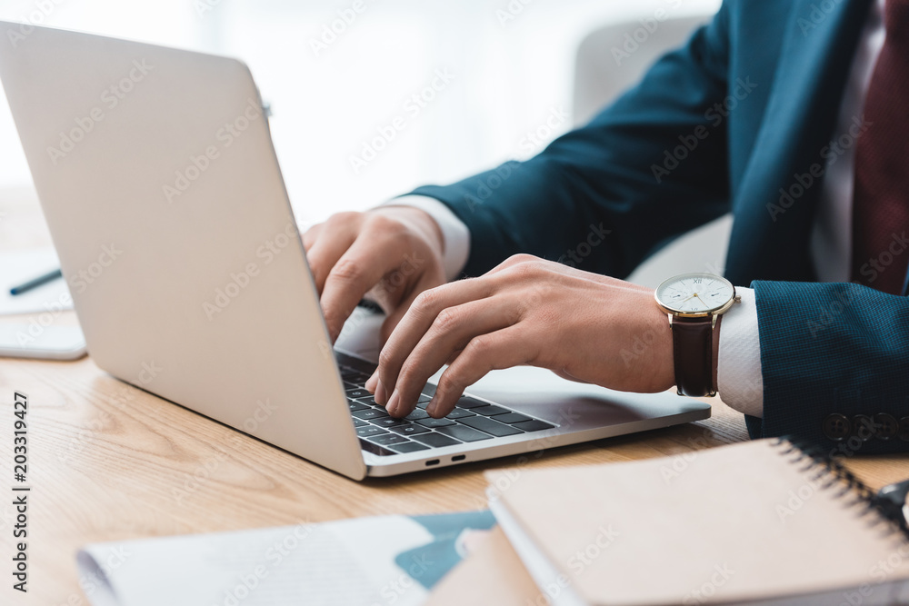 close-up partial view of businessman using laptop at workplace close-up partial view of businessman using laptop at workplace