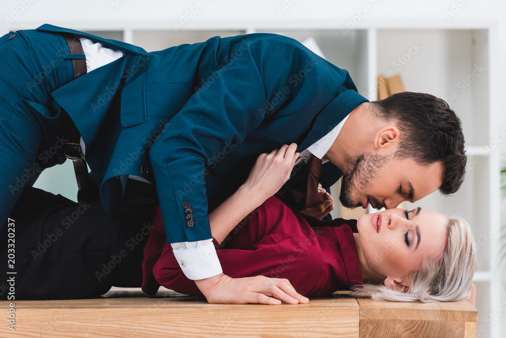side view of sexy young couple kissing on table in office Stock Photo |  Adobe Stock