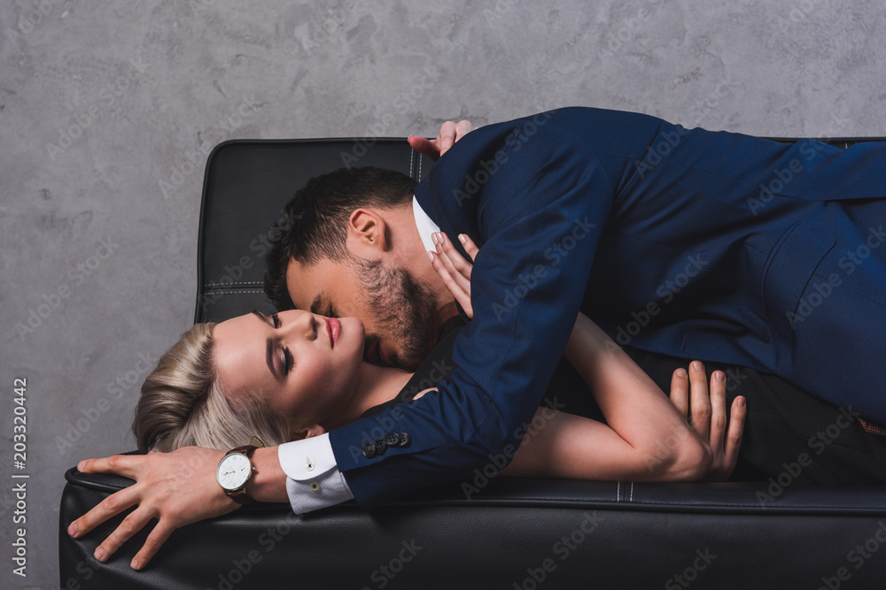 Obraz premium side view of sexy young couple kissing on couch