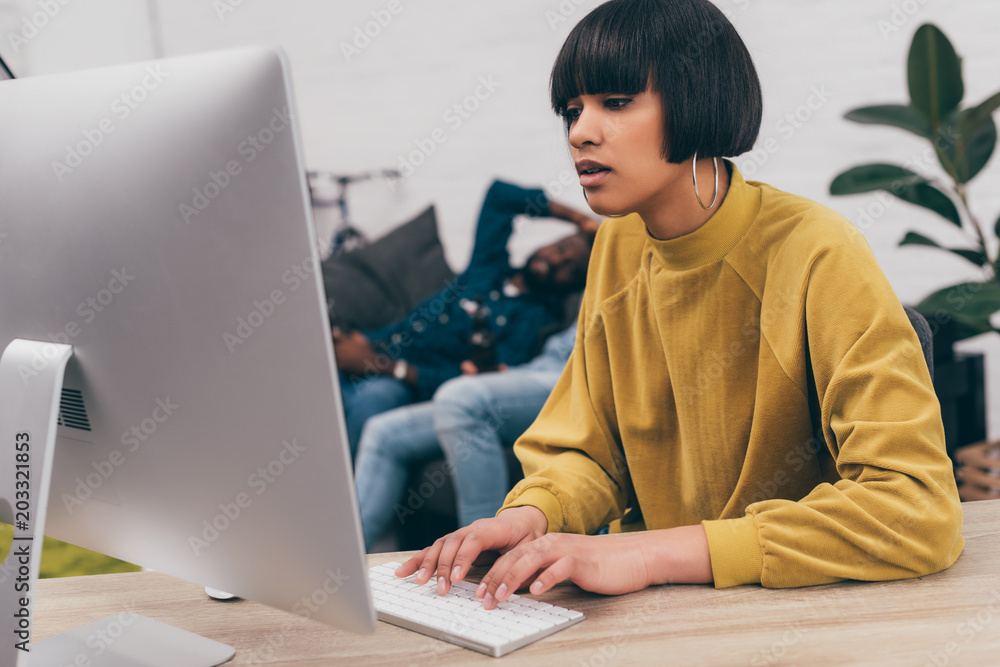 mixed race young woman typing on computer keyboard at table with