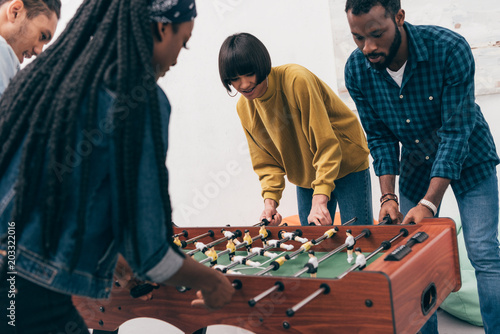 young multiethnic friends playing table soccer