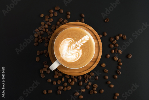 Coffee cup with wooden plate, roasted coffee beans on black background.