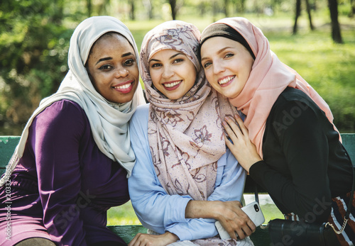 Islamic friends sitting at the park and smiling to camera