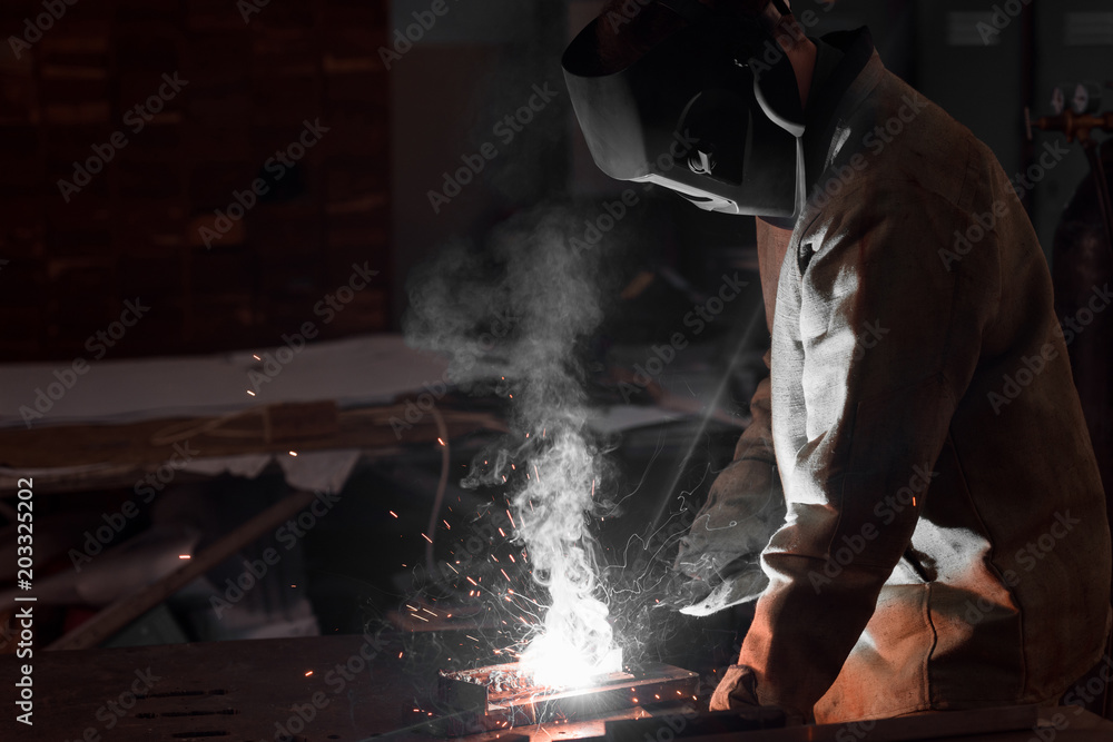 welder in protection mask working with metal at factory welder in protection mask working with metal at factory