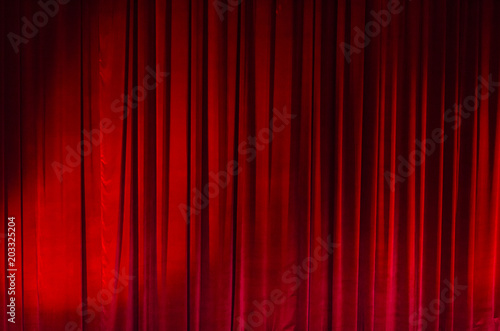 Large red curtain with spot light and fading into dark.
