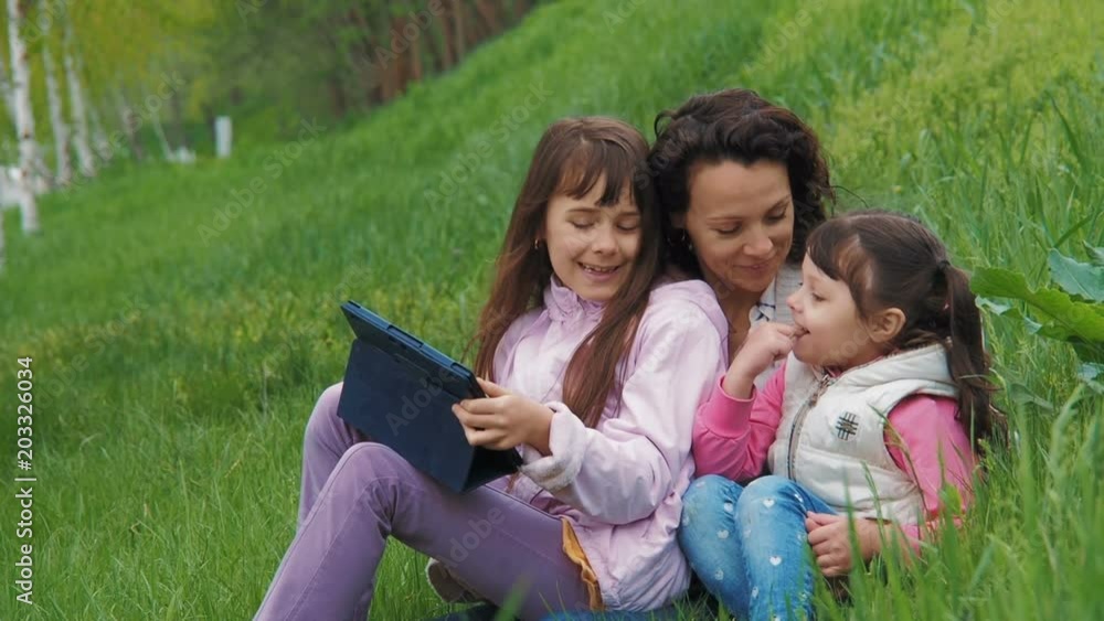 Family with a tablet on the nature. A child with mother on the grass with a tablet. Family with a tablet on the nature. A child with mother on the grass with a tablet.