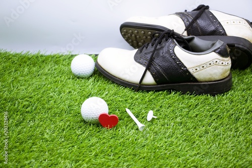 Golf ball and shoe are on green grass