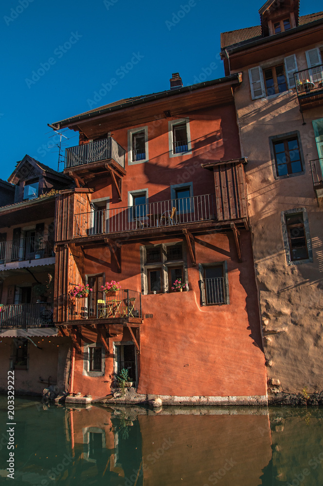 Old buildings at the city center of Annecy, in front of the channel, with blue sky and illuminated by the sundown's light. Department of Haute-Savoie, Auvergne-Rhone-Alpes region, France. Old buildings at the city center of Annecy, in front of the channel, with blue sky and illuminated by the sundown's light. Department of Haute-Savoie, Auvergne-Rhone-Alpes region, France.