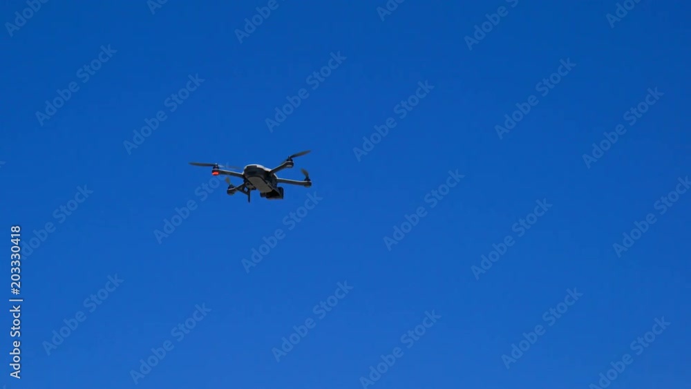 Drone taking off against a bright blue summer sky, handheld.