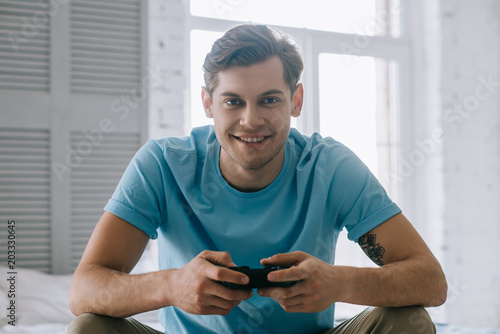 Man with joystick playing video game while sitting on bed