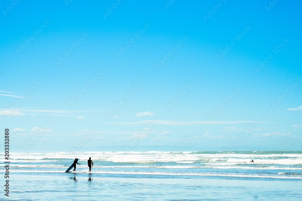 People enjoy their activities at the beautiful beach on a sunny blue sky day.