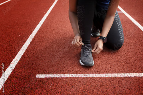 Runner tying shoelaces on run tracks lanes in stadium ready for race competition