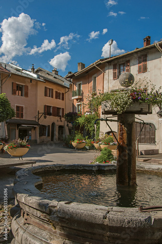 Square with stone buildings, fountain and blue sunny sky in Conflans. An historical hamlet near Albertville. Located at the department of Haute-Savoie, southeastern France.