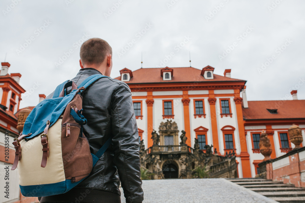 A traveler with a backpack looks at the tourist attraction. The tourist looks at the castle in the Czech Republic. Sightseeing.