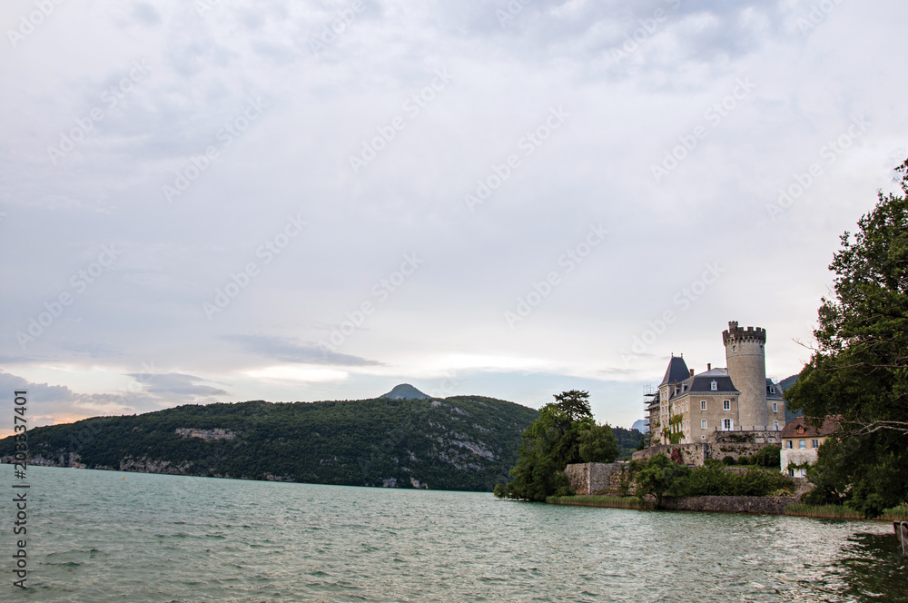 Duingt Castle with mountain landscape and cloudy sky next the Annecy Lake, near Annecy. Located at the department of Haute-Savoie, southeastern France.