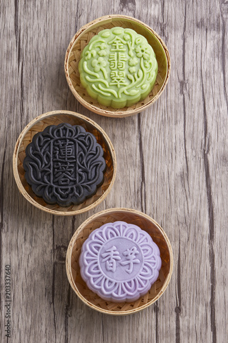 Chinese mid autumn festival foods. Snow skin mooncake on wooden table with text Green "Golden Emerald", Black "Lotus Paste" & Purple "Yam"