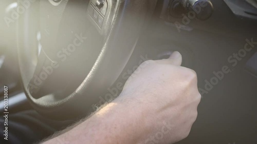 Close up of man starting car with early morning sunshine lens flare, handheld.