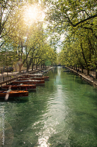 Large canal with boats and trees in the city center of Annecy. An historical and lovely lakeside town located at the department of Haute-Savoie, southeastern France. Retouched photo