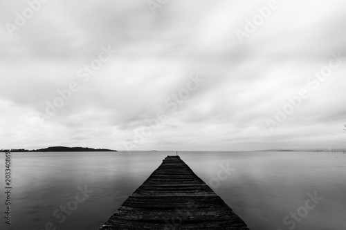 Long exposure first person view of a pier on a lake, with perfectly still water