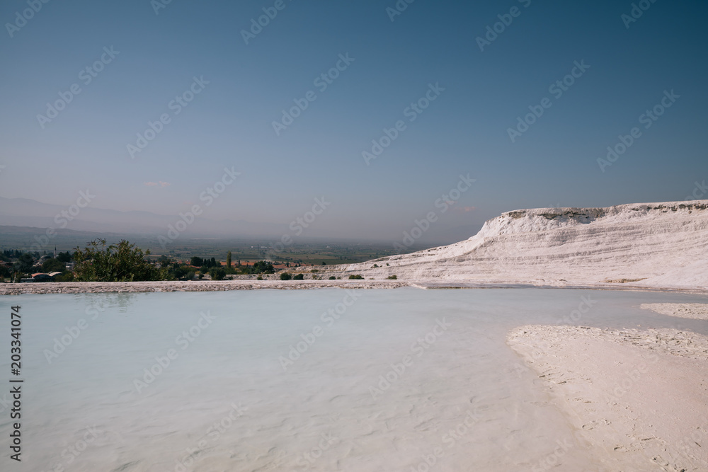 beautiful landscape with white rocks and calm water of pool in pamukkale, turkey