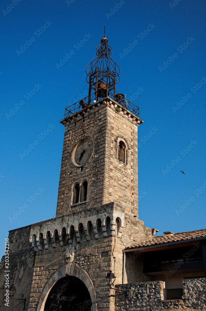 Close-up of old stone tower at sunrise, with clock and bell, in the city center of the quiet village of Le Thor. Located in the Vaucluse department, Provence-Alpes-Côte d'Azur region in southeastern F