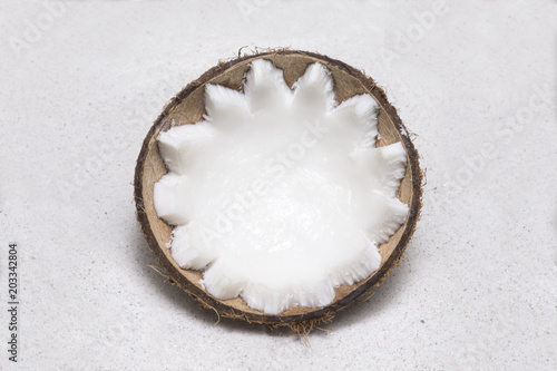 Half coconut lying in white sand