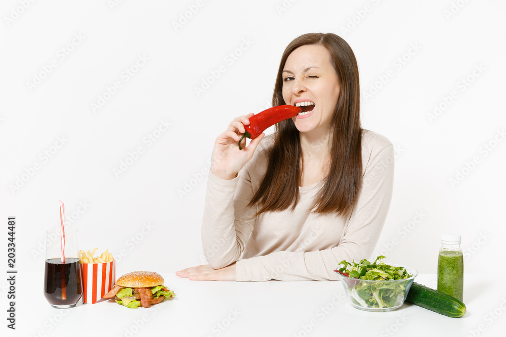 Woman with green detox smoothies, salad in glass bowl, cucumber, pepper, burger, cola in bottle isolated on white background. Proper nutrition, healthy lifestyle, classic fast food, dieting concept. Woman with green detox smoothies, salad in glass bowl, cucumber, pepper, burger, cola in bottle isolated on white background. Proper nutrition, healthy lifestyle, classic fast food, dieting concept.