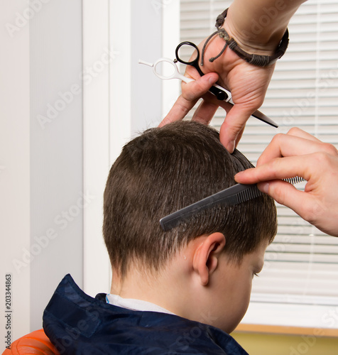 It's time for a new hairstyle. In the hands of a hairdresser there is a comb and scissors. haircut in a hairdresser's child