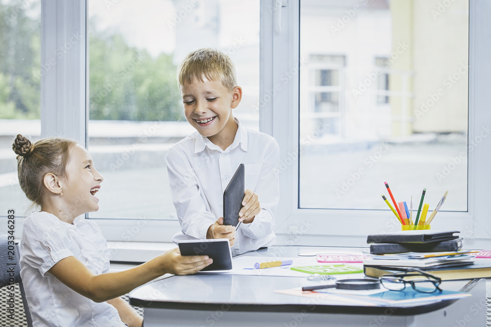 Beautiful children are students together in a classroom at the school receive education with tablets happy Beautiful children are students together in a classroom at the school receive education with tablets happy