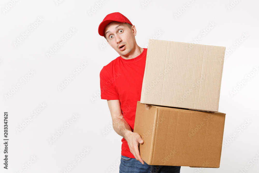 Delivery young man in red uniform isolated on white background. Male in cap, t-shirt, jeans working as courier or dealer holding empty cardboard boxes. Receiving package. Copy space for advertisement. Delivery young man in red uniform isolated on white background. Male in cap, t-shirt, jeans working as courier or dealer holding empty cardboard boxes. Receiving package. Copy space for advertisement.
