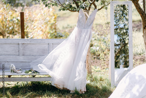 Wedding dress in the garden before the dress of the bride near the vintage bench and mirror