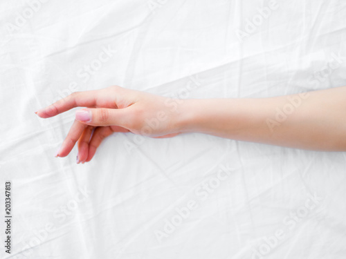 female hand on the bed. white sheets. bedroom