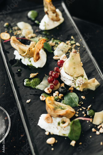 Delicious cheese pieces and berries on stone slab