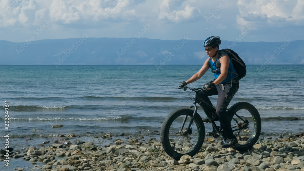 Fat bike also called fatbike or fat-tire bike in summer driving on the beach. The guy is going straight on the beach. On the sand on such a bike ride is not difficult. Fat bike also called fatbike or fat-tire bike in summer driving on the beach. The guy is going straight on the beach. On the sand on such a bike ride is not difficult.