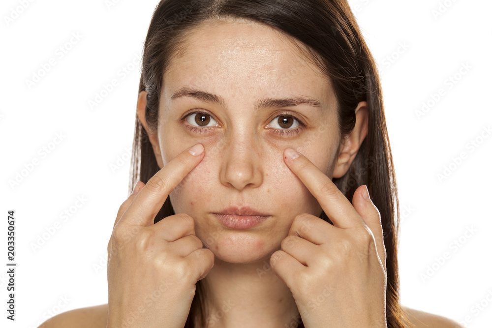 Beautiful young woman touch her face under eyes on white background Beautiful young woman touch her face under eyes on white background